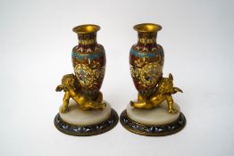 A pair of miniature French champleve enamel vases, being supported by ormolu cherubs,