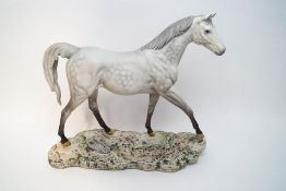 A large Beswick model of a dapple grey horse, matt finish, on a naturalistic base,