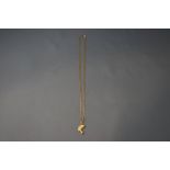 A 9 carat gold chain, of filed curb links, 45 cm long, and a Nefertiti charm attached, 3.