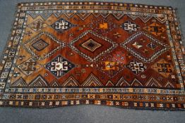 A Middle Eastern rug, the central field with three rows of diamond motifs over a rust red ground,