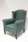 An Edwardian wingback armchair with sea-green patterned upholstery,