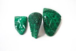 Three pieces of malachite, each carved with a human face,