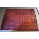 A Turkish carpet with repeating star motifs over a red ground, within narrow borders,