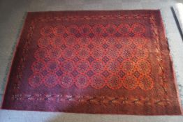A Turkish carpet with repeating star motifs over a red ground, within narrow borders,