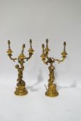 A pair of 19th century ormolu three branch candelabra, each cast with a cherub holding aloft a horn,