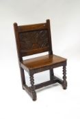 A 19th century oak side chair with heavily carved back, depicting a plant within a vase,