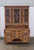 An Arts and Crafts oak sideboard with three drawers flanked by cupboards,