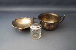 A silver two handled bowl; with a small silver footed dish; and a small silver topped toilet jar;