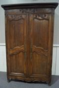 A 19th century French oak armoire with two carved panelled doors,