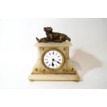 An alabaster mantel clock, surmounted by a figure of a dog and gamebird, with winding key,
