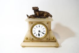 An alabaster mantel clock, surmounted by a figure of a dog and gamebird, with winding key,