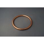 A 9 carat rose gold bangle, of hollow round section, 6mm wide, internal diameter 7.