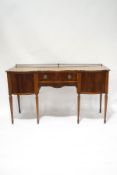 An Edwardian mahogany serpentine sideboard, the central drawer flanked by cupboards,