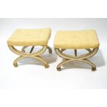 A pair of white painted cross frame stools, with pale yellow buttoned seats,