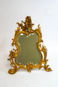 A Victorian strut mirror with bevelled glass, Rococo style scroll frame and cherub mount,