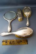 A silver backed hand mirror; three silver backed brushes;