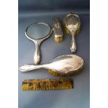 A silver backed hand mirror; three silver backed brushes;