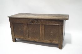 An 18th century oak six plank coffer with carved flower detail,