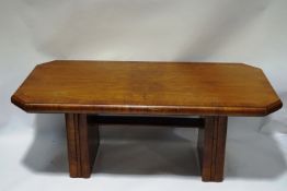 An Art Deco walnut dining table, the top with canted corners upon a stretchered base,
