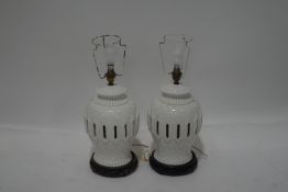 A pair of Chinese pierced porcelain table lamps, with carved hardwood stands,