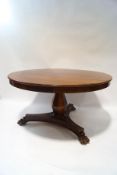 A William IV mahogany breakfast table, the triform base with heavily carved lion's paw feet,