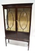 A late 19th century mahogany display cabinet on stand, with oval and sectioned glazed panes,