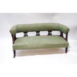 A Victorian mahogany salon settee with green patterned upholstery,