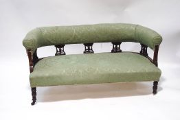 A Victorian mahogany salon settee with green patterned upholstery,