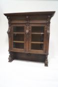 A Victorian carved oak display cabinet with two glazed doors enclosing two shelves on carved and
