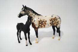 Two Royal Doulton horses: an Appaloosa, 21cm high, and a foal, matt black finish,