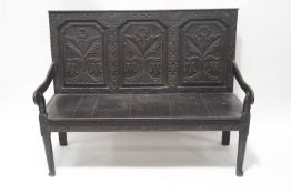 A Victorian oak settle, the triple panelled back carved with flowers,