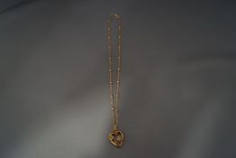 A hollow heart shaped pendant, stamped 'carat', stone and split seed pearl set,