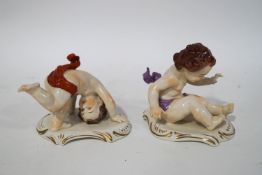 A pair of Continental figures of Putti, one in a seated pose, the other standing on his head,