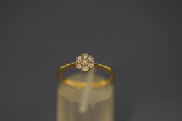A seven stone diamond flower head cluster ring, stamped '18ct', set with single cuts,