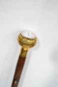 A wooden and brass inlaid walking stick with clock inset knop