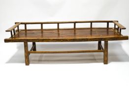 A 20th century Chinese day bed, with three quarter gallery surround and inset bamboo seat,
