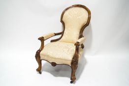 A Victorian balloon back armchair with carved walnut show frame on cabriole legs and casters