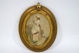 An early 19th century silkwork picture of a young girl holding corn, within a later oval frame,