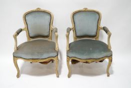 A pair of Louis XV style painted open armchairs with gilt detail