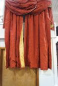 A pair of red and gold flower embroidered curtains with attached pelmet,
