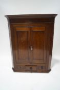 A George III oak and mahogany corner cabinet, panelled cupboard doors enclosing two shelves,