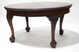 An Edwardian mahogany oval dining table with carved flower border on ball and claw feet,