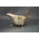 A silver sauceboat, Birmingham 1934, with leaf capped flying scroll handle, tongue and dart border,