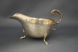 A silver sauceboat, Birmingham 1934, with leaf capped flying scroll handle, tongue and dart border,