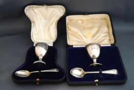 A silver egg cup and spoon, cased and monogrammed; with another silver egg cup and spoon,