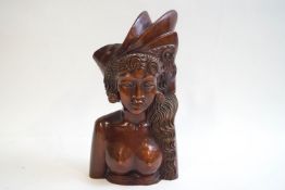 A Balinese hardwood bust carved as a woman with long hair and a headdress,