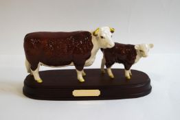 A Beswick Hereford cow and calf, mounted on a wooden plinth, 1360/1827C,