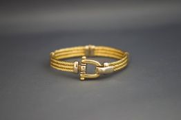 A two colour hinged bangle, marked 585, with a stirrup catch,