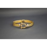 A two colour hinged bangle, marked 585, with a stirrup catch,