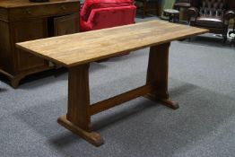 An oak refectory style table with style ends linked by a stretcher and flared feet,
